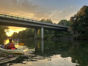 kayaker near a bridge at sunset